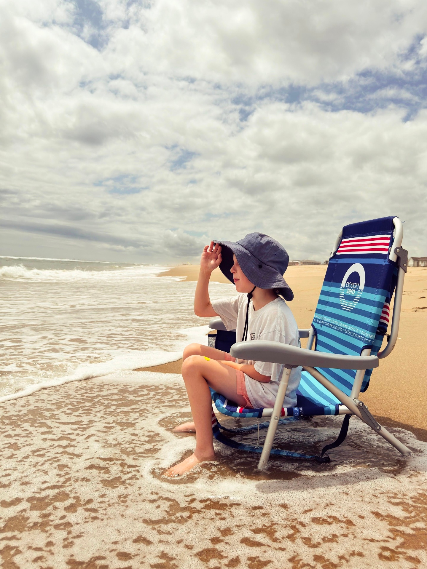 Child sitting in a beach chair at the shoreline